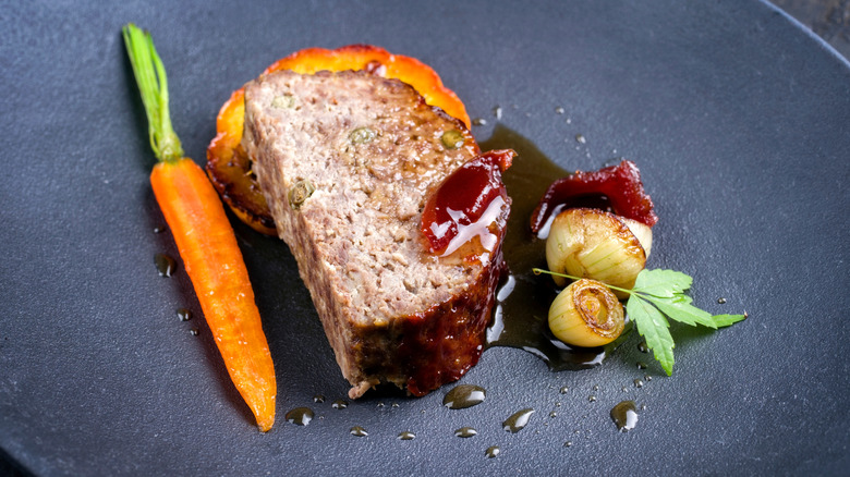 Glazed meatloaf with carrot and orange on plate