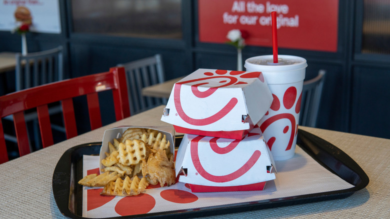 Chick-fil-A fries, two sandwich boxes, and a drink sitting on a tray