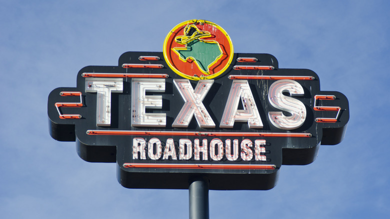 A Texas Roadhouse sign with the sky in the background