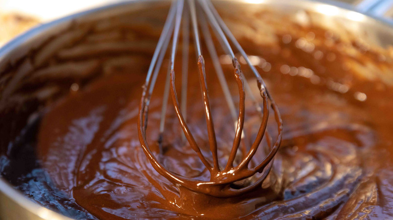 a whisk partially submerged in a bowl of brownie batter