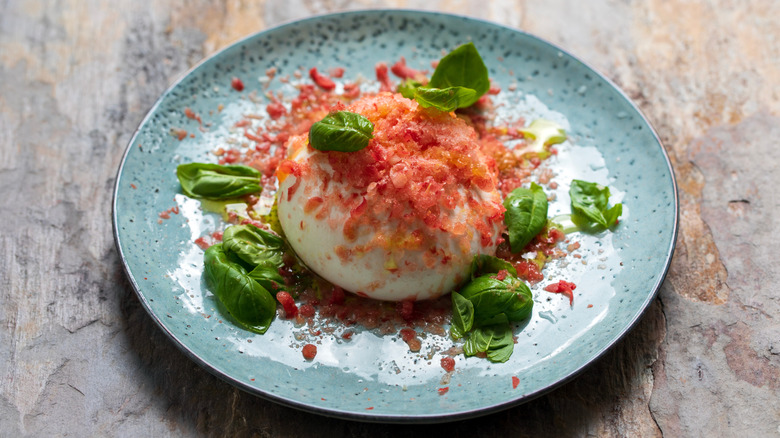 Shaved frozen tomato on burrata cheese with fresh basil