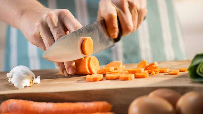 person chopping carrots on board