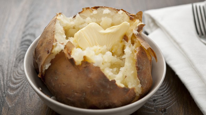 Opened baked potato in a dish with butter inside