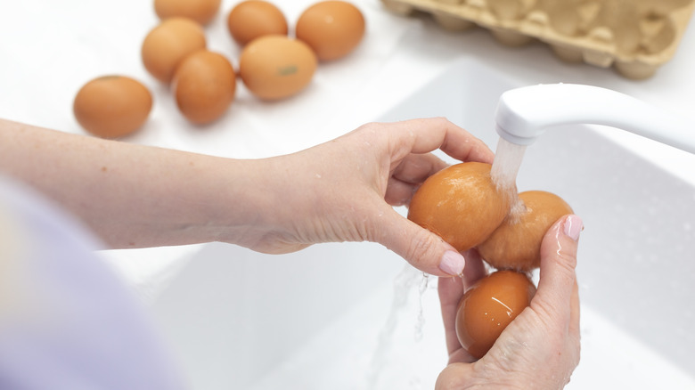 A person washing brown eggs under a faucet