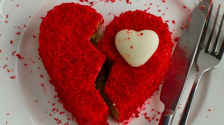 Red broken heart-shaped cake next to silverware