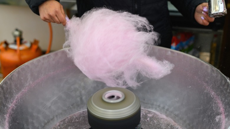 A person spinning cotton candy in a machine.