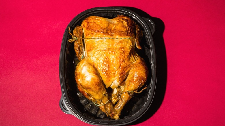 A rotisserie chicken in its container, viewed from above.