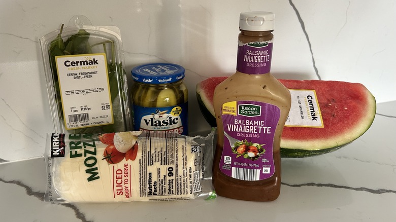 Ingredients for a watermelon sandwich including basil, pickles, watermelon, mozzarella, and balsamic