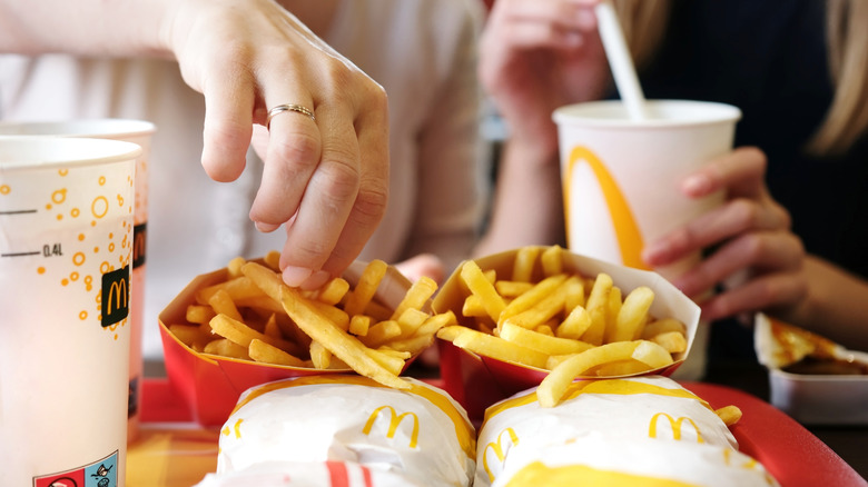 Person picks up a fry from a McDonald's tray of food