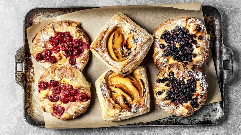 Six danish pastries, two of each kind raspberry, peach, and blueberry.