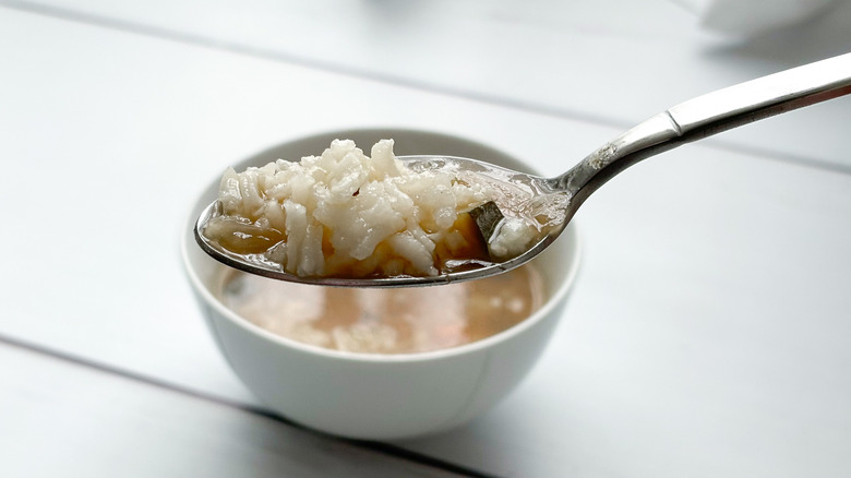 White rice in soup broth sitting on spoon