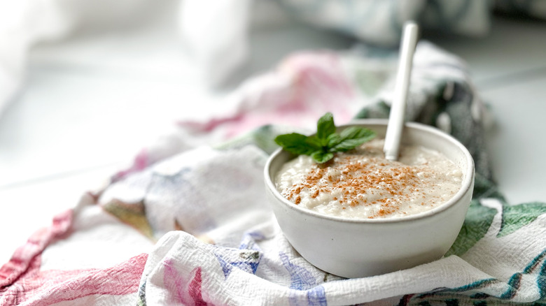 Rice pudding in ceramic bowl with spoon and mint leaves