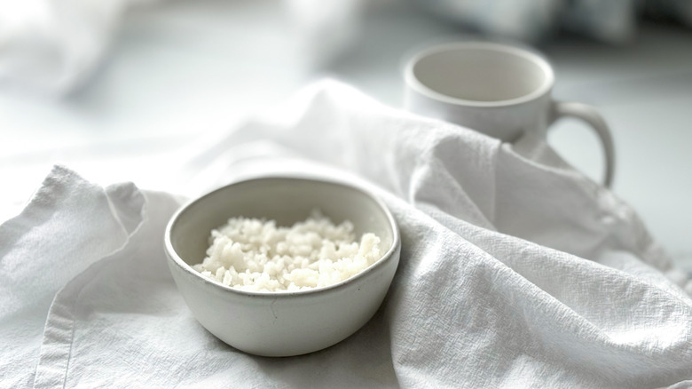 Bowl of white rice with mug in background