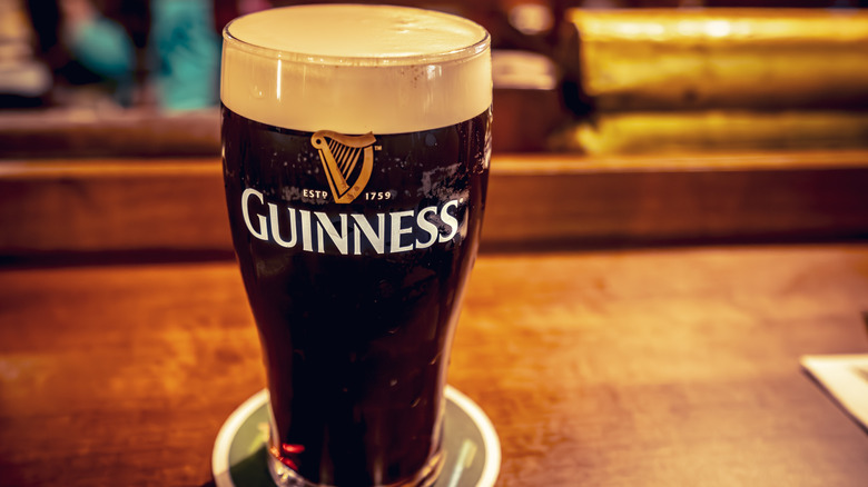 A pint of Guinness in a branded glass, sitting on a bar