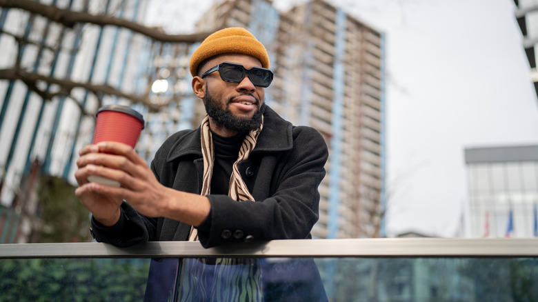 A man drinking coffee outside in a to-go cup