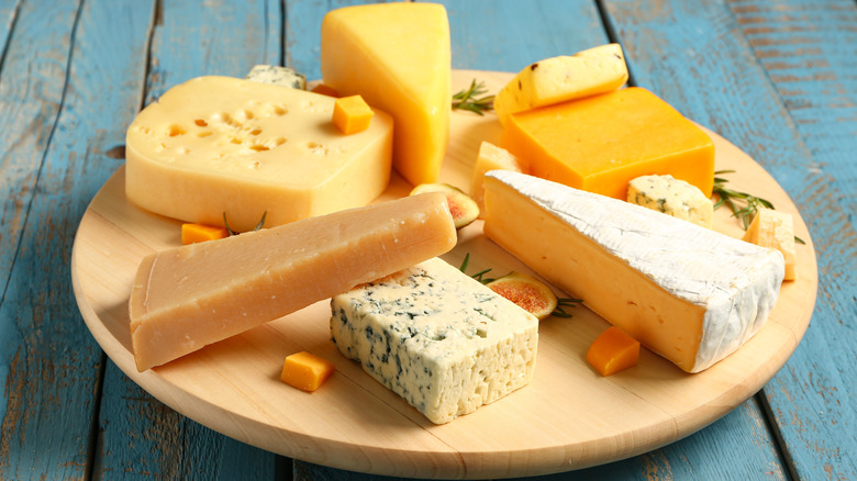 Blocks and wedges of assorted cheeses on a wooden board