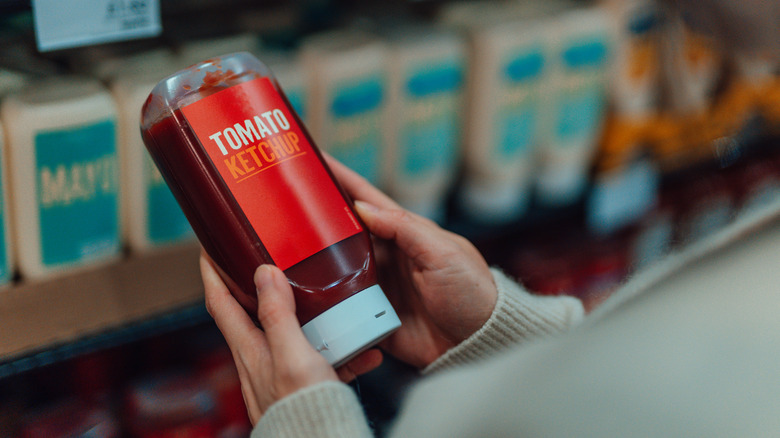 Person holding ketchup in a bottle