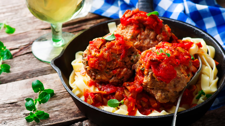 Marinara sauce over meatballs and noodles in an iron skillet