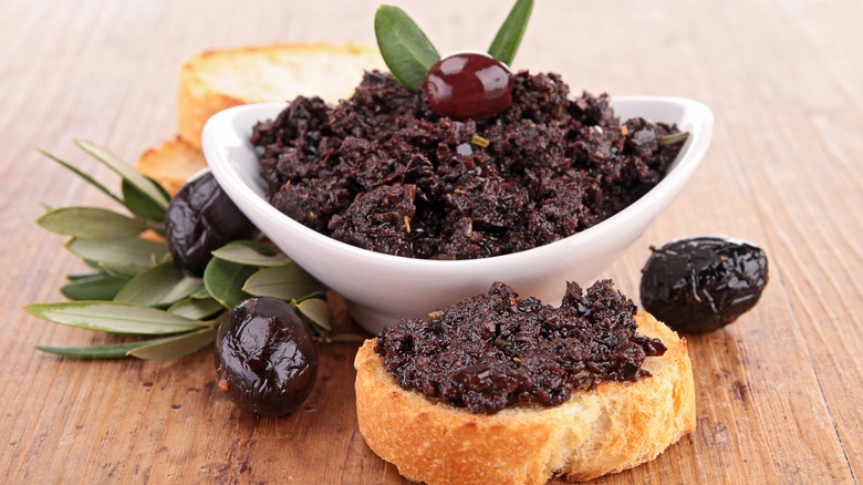 Olive tapenade in bowl and on spread on bread