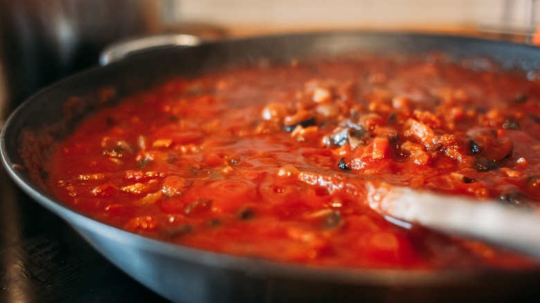 Tomato puree in skillet with wooden spoon