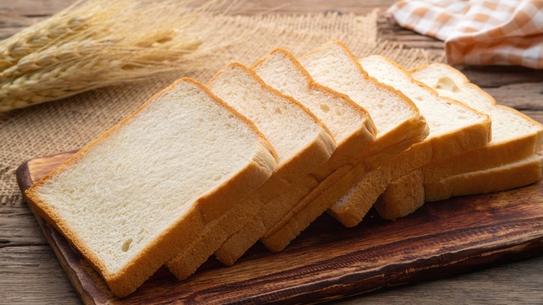 Slices of white bread on a wooden board.