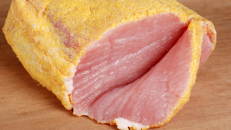 Peameal bacon loin sitting on a wood surface.