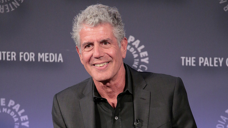 Anthony Bourdain sitting down and smiling at a media event