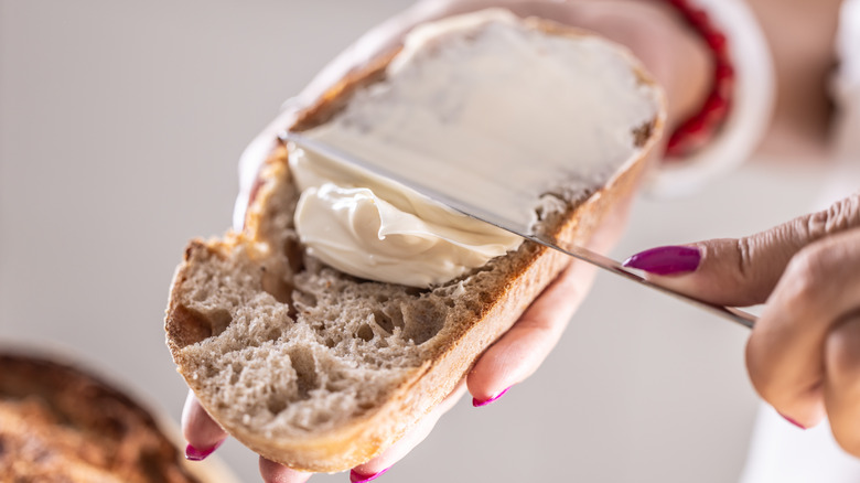 Someone spreading butter onto bread