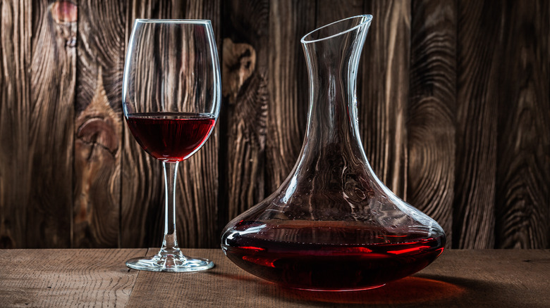 Glass and decanter full of red wine on a wooden table/background