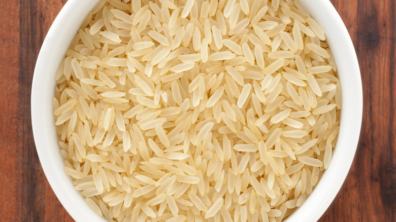 Top view of a bowl of parboiled rice on a wooden table