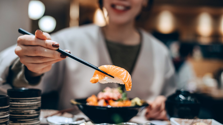 A person holding sushi with chopsticks