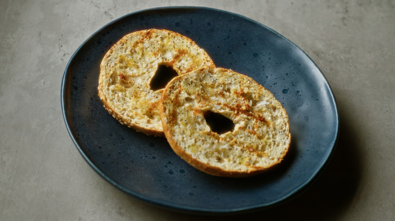 A toasted sesame bagel on a black plate