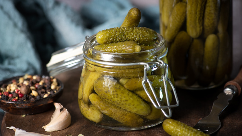 A glass container of pickles on a wooden surface