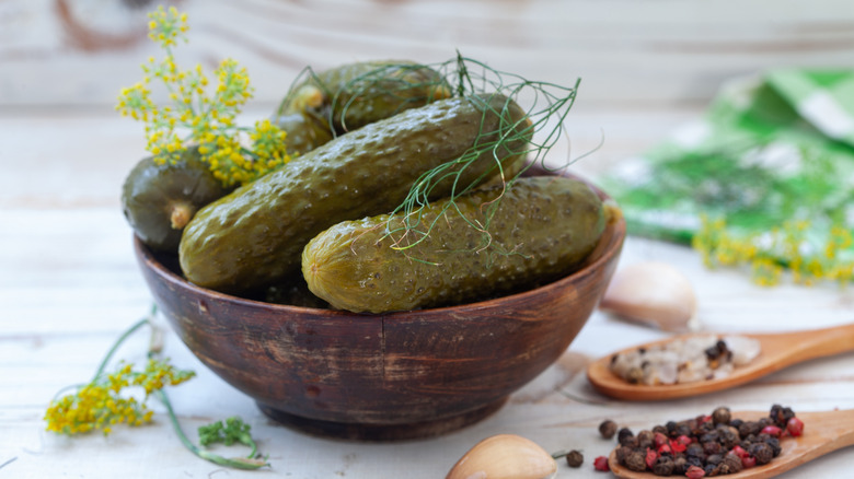 A bowl of pickles cucumbers garnished with fresh herbs