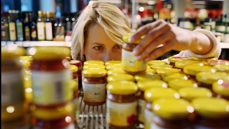 Woman checking label on glass jar product