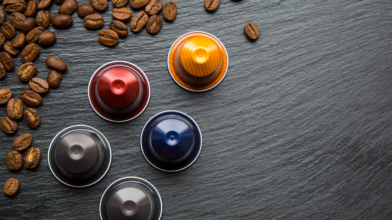 Nespresso Original pods on a dark surface with coffee beans