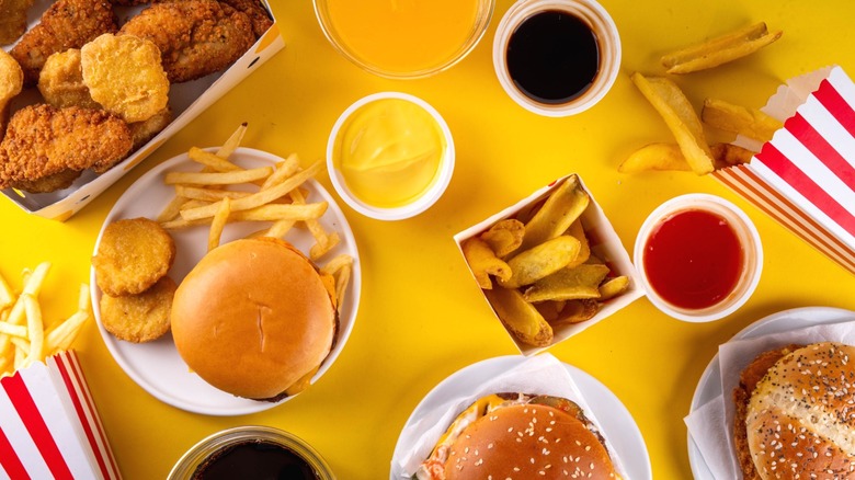 burgers, fries, chicken nuggets, and sauces arrayed against a yellow background