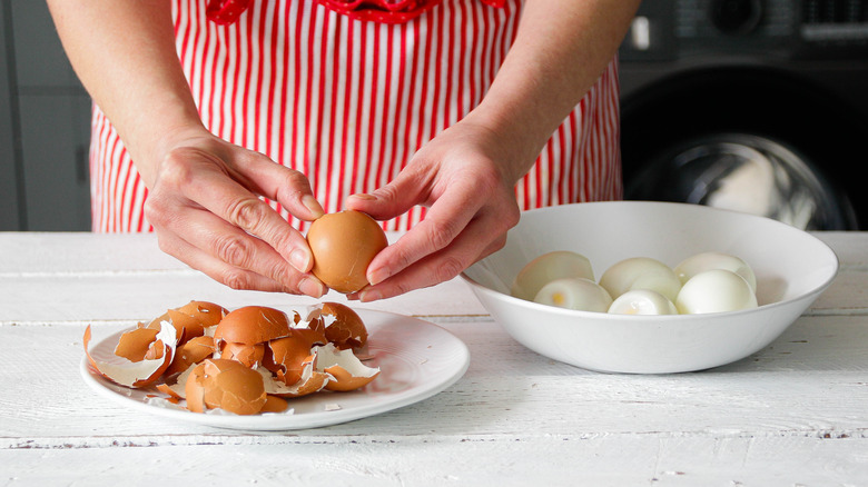 hands peeling hardboiled egg