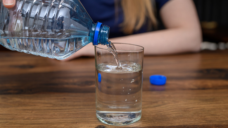 woman pouring water into glass on a wooden table