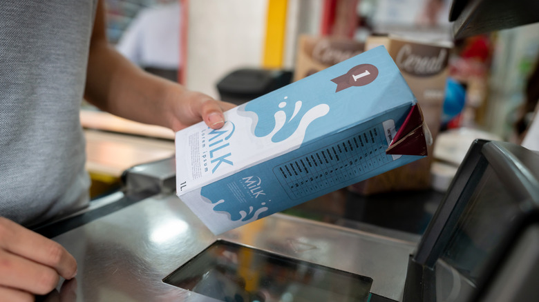 Person at grocery store scanning a box of milk