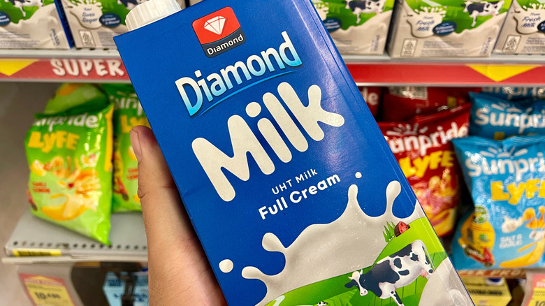 Hand taking a box of milk from a grocery store shelf