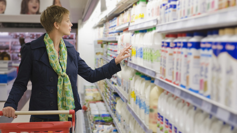 Woman shopping for refrigerated milk in dairy aisle