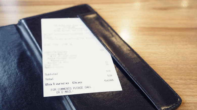 A restaurant bill sitting in a black check holder,