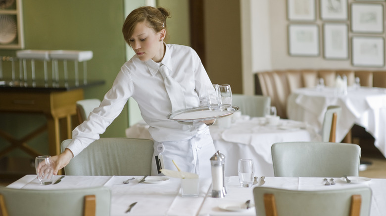 A restaurant server putting down a clean glass on table