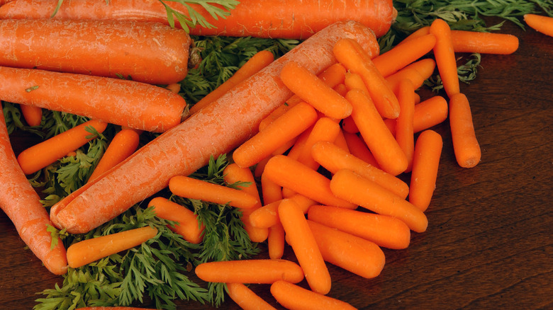 Full grown and small, baby carrots on a table