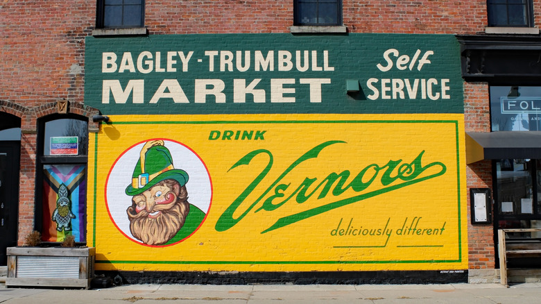 A big yellow sign on the side of a brick building advertising Vernors drink