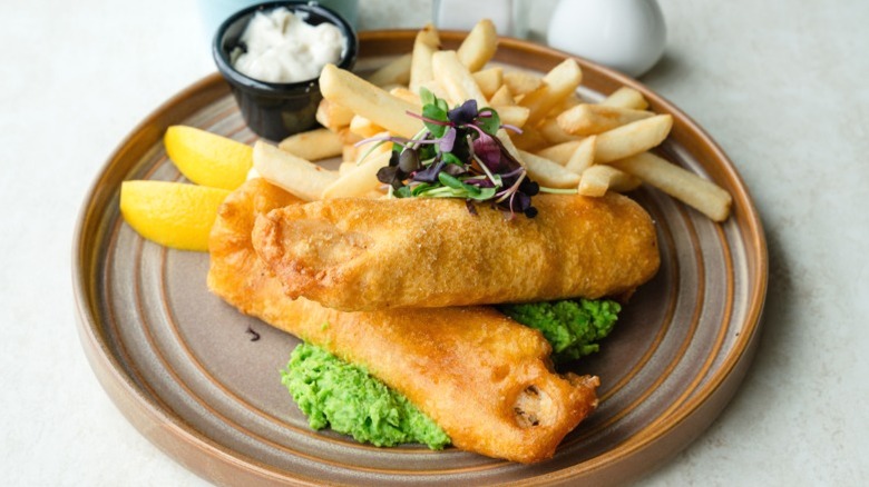 A plate of fish and chips, served with tartar sauce and mushy peas