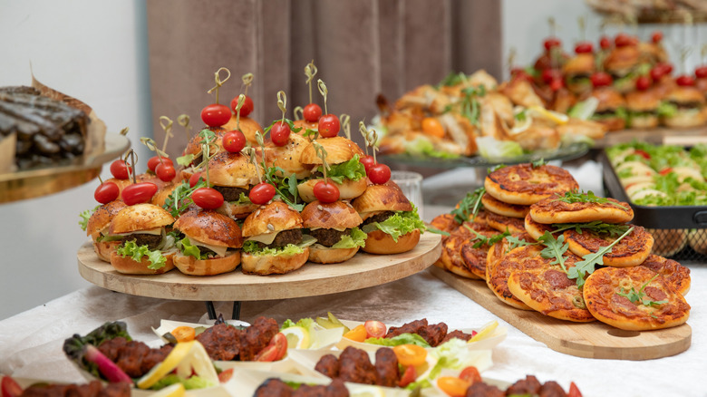 Various appetizers like sliders and mini pizzas as part of a buffet spread