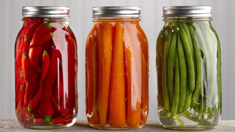 three jars of pickled chili peppers, carrots, and green beans