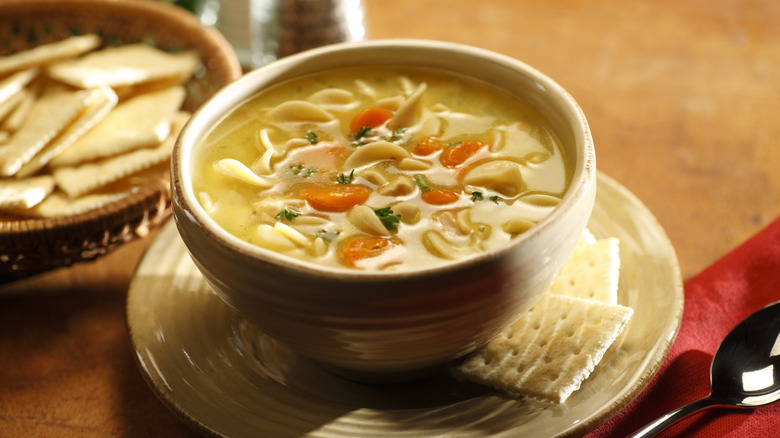 Chicken noodle soup in a bowl with crackers